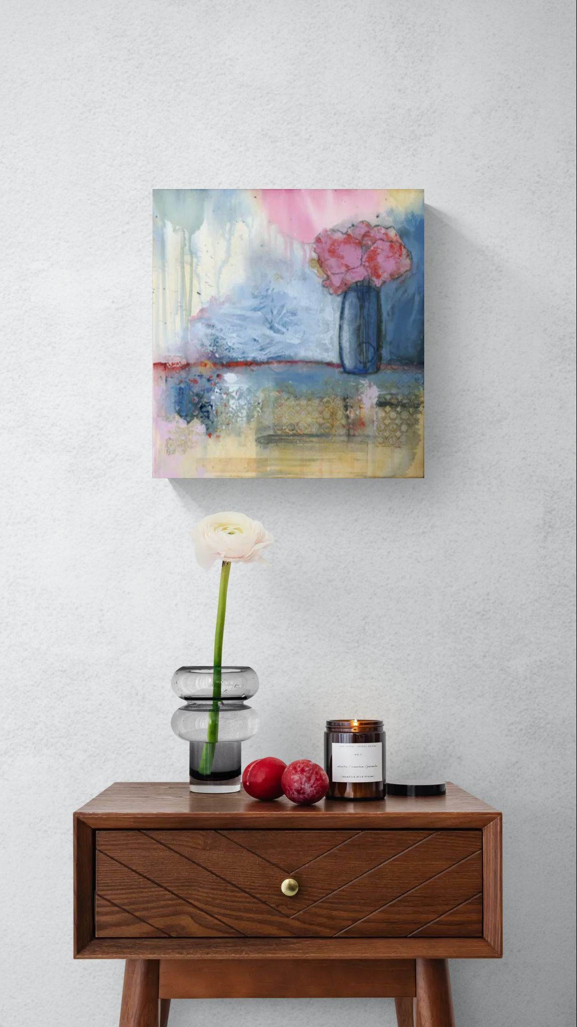 Original dreamy colorful floral wall art, titled "Auroras and Hydrangeas," by Little Haven Art Studio artist Amanda Craig, depicting a blue vase with red and pink flowers and an abstract background in red, pink, green, blue, and yellow, in hallway above table with flower and vase.