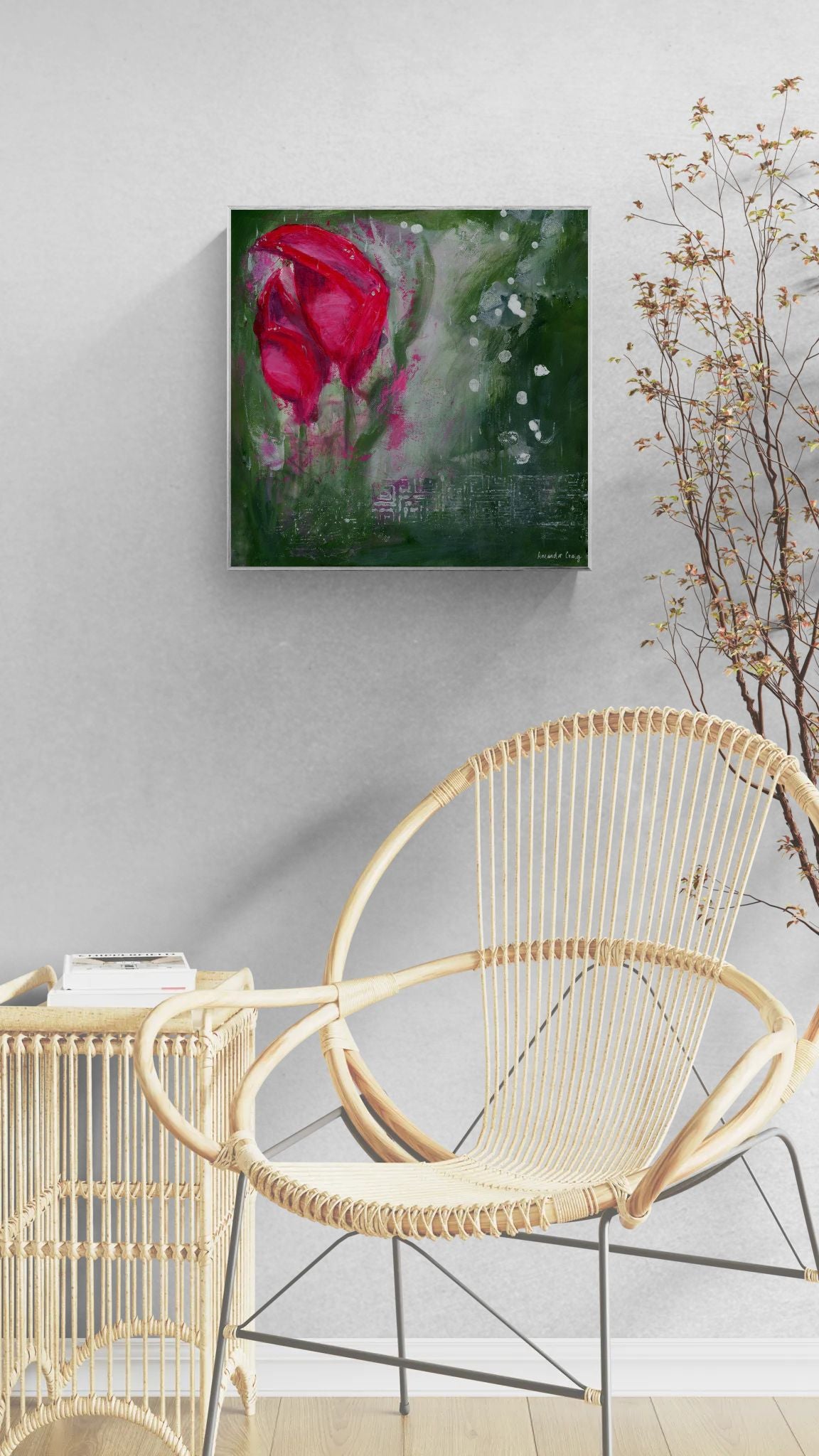 Original floral mixed media painting on abstract background titled, "Living Hope," by Amanda Craig of Little Haven Art Studio, in magenta pink, ruby red, emerald green, gray, and metallic silver, with silver tone floating frame hanging on a gray wall above boho chair.