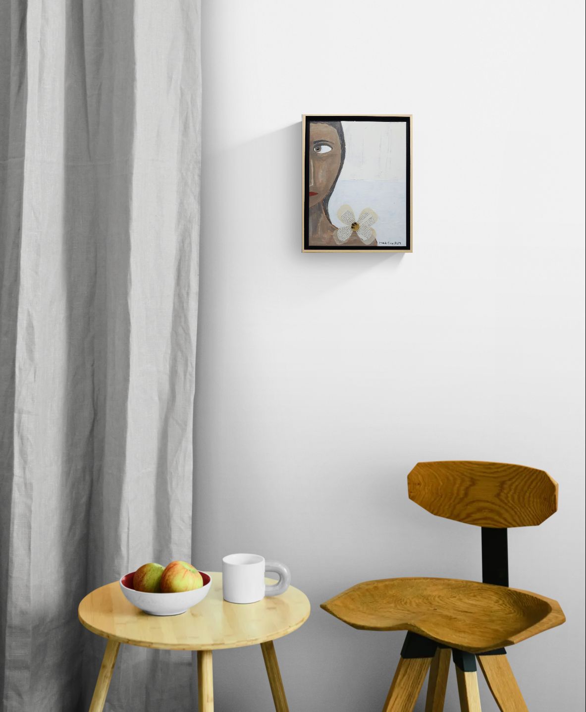 Original mixed media wall art, titled "Anger" in the Beauty for Ashes series by Little Haven Art Studio, depicting half of an angry face, with flower collage and plaster elements, hanging above small wooden table and chair.