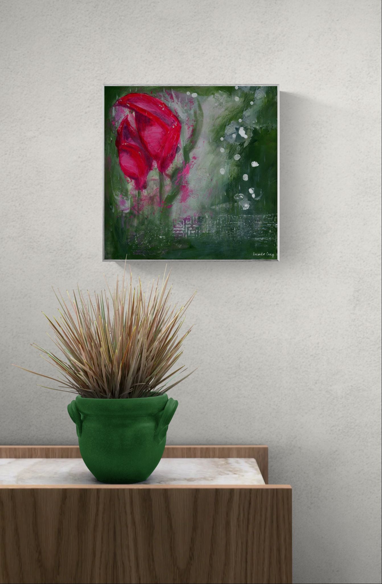 Original floral mixed media painting on abstract background titled, "Living Hope," by Amanda Craig of Little Haven Art Studio, in magenta pink, ruby red, emerald green, gray, and metallic silver, with silver tone floating frame hanging on a gray wall above plant.