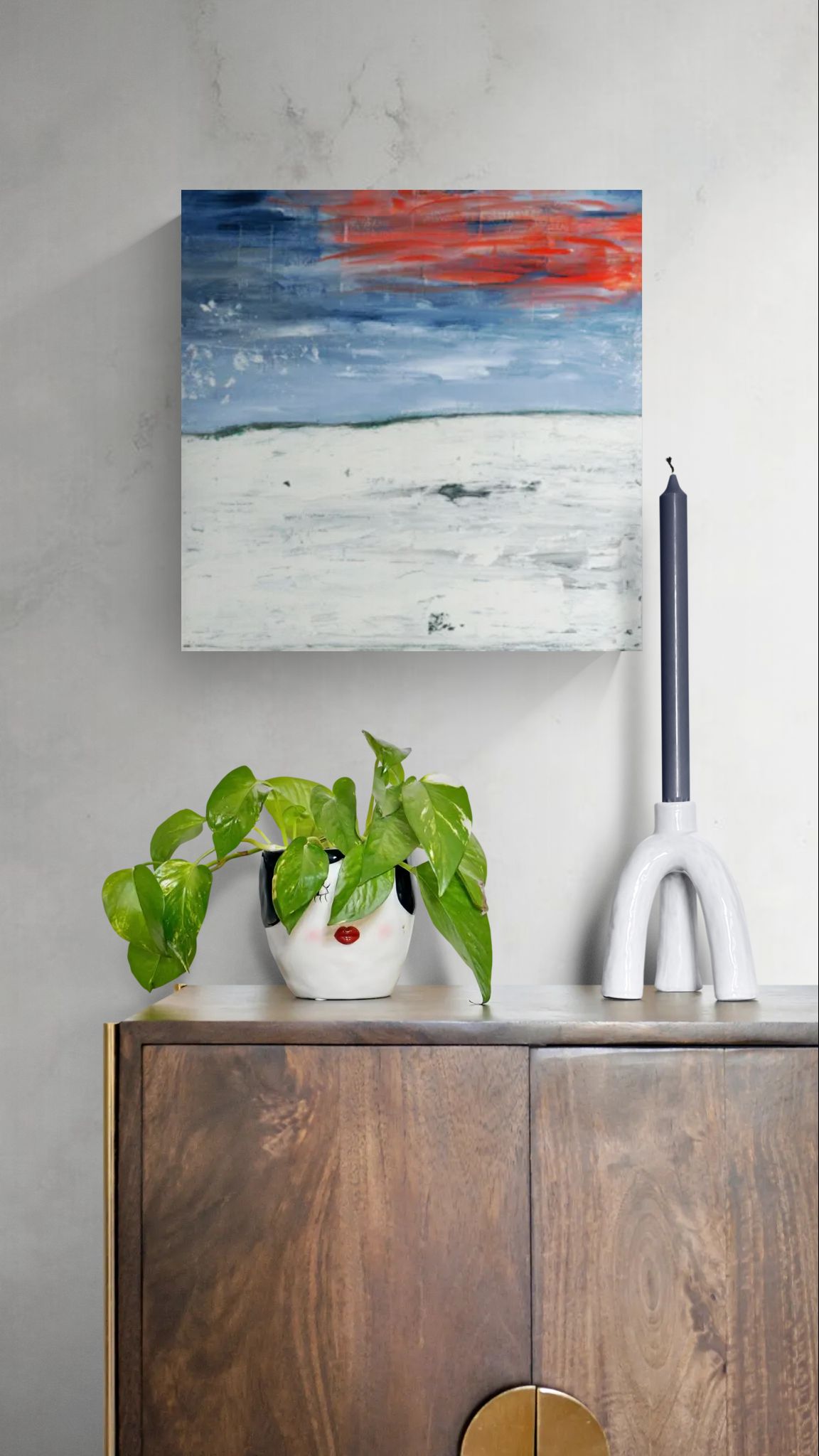 "New Beginnings" abstract original wall art landscape painting with red and blue elements by Little Haven Art Studio hanging above wooden cabinet with candle and plant.