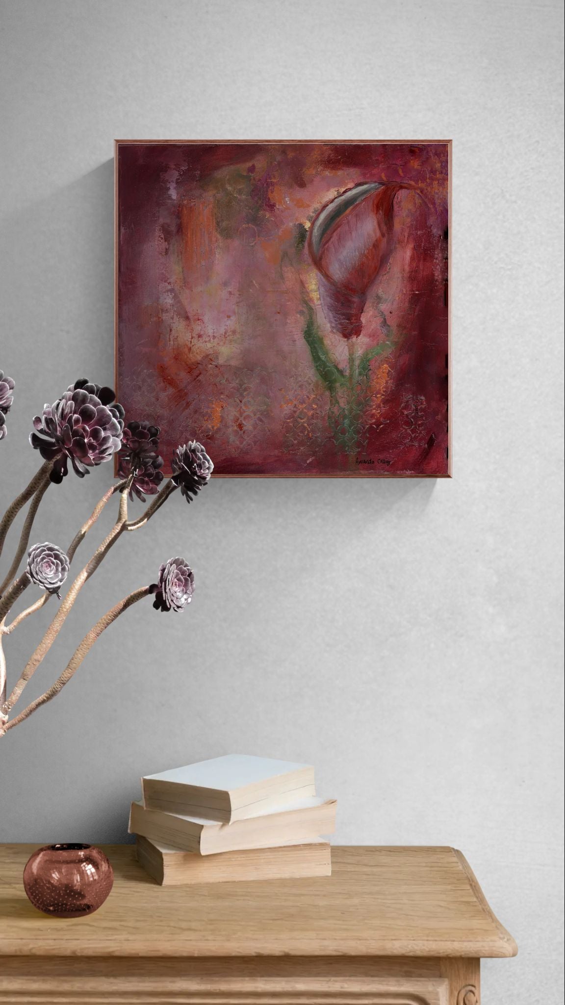 Original floral mixed media painting on abstract background titled, "Redeemed," by Amanda Craig of Little Haven Art Studio, in garnet with metallic copper, with copper tone floating frame hanging in hallway above wooden cabinet.