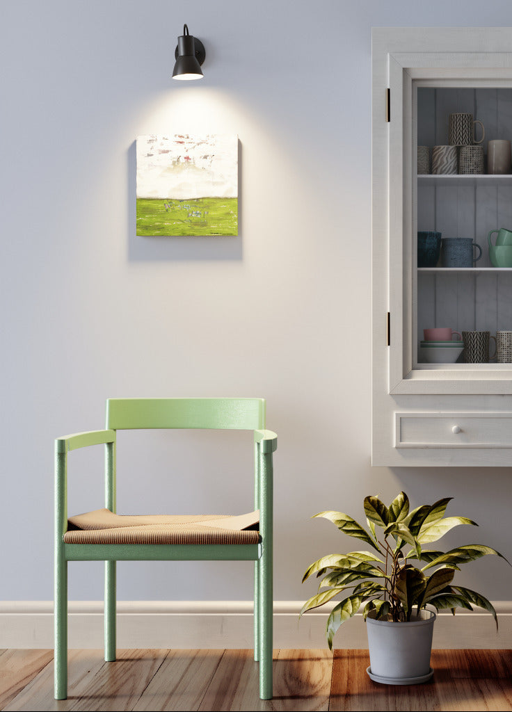 "Searching for Something" original abstract canvas wall art in green and white, by Amanda Craig of Little Haven Art Studio hanging above chair with spotlight, next to cabinet.