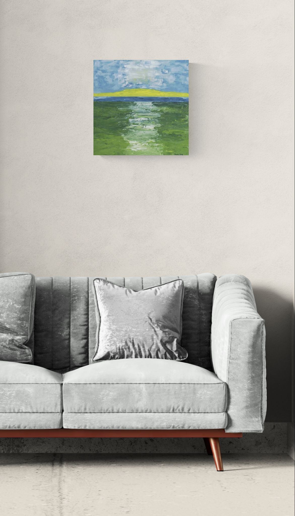The Golden Strand original wall art of abstract landscape of path through field and water by Amanda Craig, Little Haven Art Studio, in green, blue, white, and yellow hanging above gray sofa.